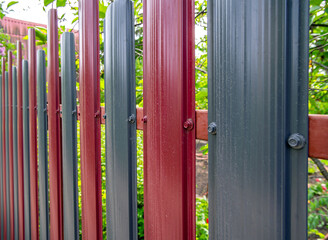 Fototapeta premium Fragment of a fence made of multi-colored metal euro picket fence