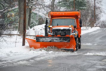 snowplow truck working on removing snow on residential street
