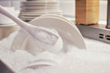 Dishwashing brush with soapy foam. Kitchen sink filled with water and detergent. Washing dishes.