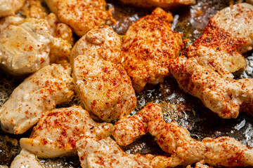 chicken fillet fried in spices and oil crispy crust in a frying pan