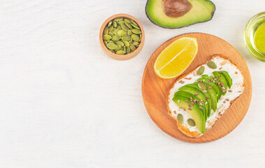 Avocado toasts with cream cheese and seeds on white table background, top view