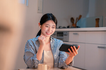 夜に家でスマホでスポーツ観戦をする若い女性