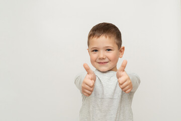 portrait of happy child on white background. little boy thumbs up, showing gesture - super. little blue-eyed boy with fair skin 5 years old