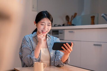 夜に家でスマホでスポーツ観戦をする若い女性