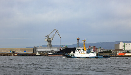 Fototapeta premium Large crane works on large coal stockpile at Osaka port.