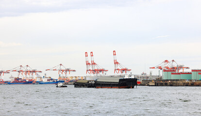 Container port at Osaka Japan, container crane at Industrial port for cargo container ship. Cargo transportation and activity at modern shipping container terminal.