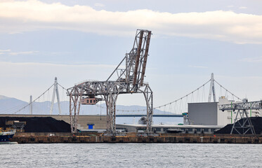 Large crane works on large coal stockpile at Osaka port.