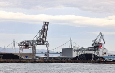 Large crane works on large coal stockpile at Osaka port.