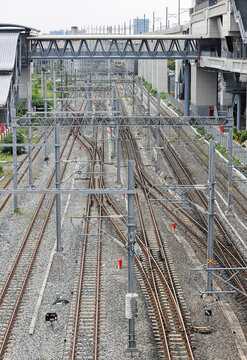 Aerial view of Infrastructure of railway tracks equipped with overhead electric poles in parallel to high powered supply lines in suburban.