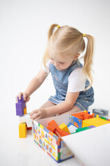 Educational Toys: The Child Develops Motor Skills With The Help Of Colorful Cubes on a white background. The girl is playing with cubes