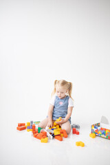 Educational Toys: The Child Develops Motor Skills With The Help Of Colorful Cubes on a white background. The girl is playing with cubes