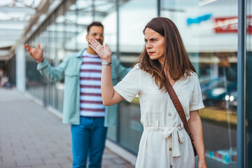 Woman Walking Away From Man Outdoors in Urban Setting with Frustrated Expressions