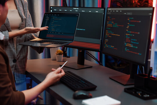 Serious of IT developers discussing intelligent website development coder system running data online two screens with laptop showing information network at neon light room at modern office. Infobahn.