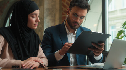 Two diverse business partners businessman businesswoman signing contract document credit loan insurance together Arabian Indian man muslim woman in hijab conclude deal partnership agreement at office