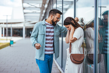 Man Yelling at Woman Near Glass Wall in Modern Urban Setting