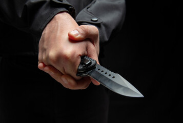 Criminal holding a knife with both hands closeup, armed attack concept.