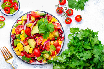 Corn salad with red beans, avocado, tomatoes, onion and cilantro. White background, top view