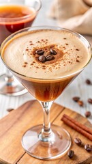 Espresso martini with frothy top, coffee beans, and cinnamon for a cozy and inviting presentation.