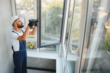 Construction worker installing window in house. Handyman fixing the window with screwdriver
