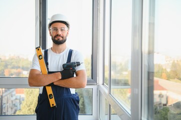 Construction worker repairing plastic window with screwdriver indoors, space for text.