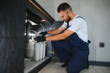 Plumber installs or change water filter. Replacement aqua filter. Repairman installing water filter...