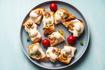 Mini toast with cottage cheese, quail eggs, cherry tomatoes, mushrooms and microgreens on a blue plate. Copyspace