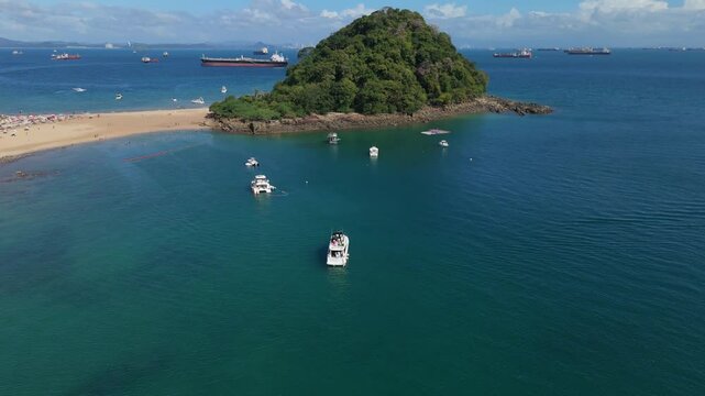 Aerial views of the beach on a sunny day of the island of Taboga in Panama, in the background the ships at the entrance of the Panama Canal.
