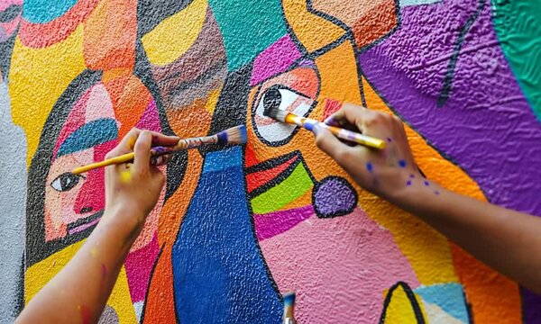Collaborative Mural Painting: Hands Adding Vibrant Colors to Abstract Faces