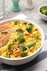 Tasty rice with vegetables and chicken on table, closeup