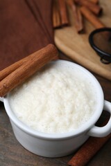 Delicious rice pudding with cinnamon sticks on wooden table, closeup