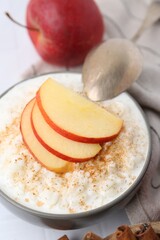 Delicious rice pudding with apples and cinnamon on white table, closeup