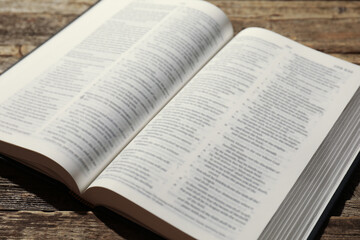 Open Holy Bible in English language on wooden table, closeup