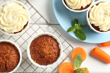Delicious carrot muffins with fresh vegetables and mint on white wooden table, flat lay