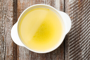 Tasty chicken bouillon in bowl on wooden table, top view