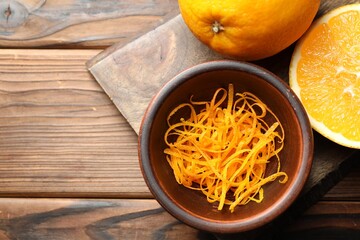 Orange zest and fresh fruits on wooden table, top view. Space for text