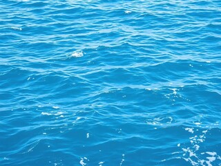 Smooth pure blue turquoise water texture of the ocean sea with white foam and gentle waves creating a serene and calming natural background, foam, waves