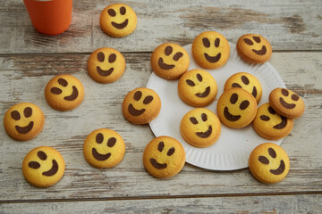 Cookies in the shape of smiling emojis scattered on a wooden table, good mood, friendliness and warmth, good family atmosphere, happiness and joy.