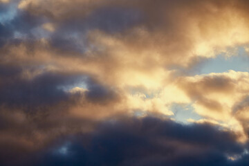 Calm winter sky with gray clouds softly lit by golden sunlight.