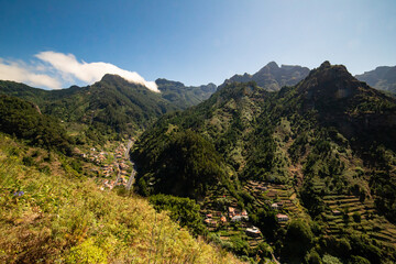 Sunlight cascading over Madeira’s green mountains, highlighting terraced farmland and winding roads through the serene countryside.