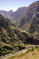 Sunlight cascading over Madeira’s green mountains, highlighting terraced farmland and winding roads through the serene countryside.