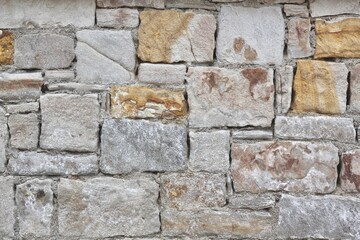 Stone wall texture background - grey  white yellow stone siding with different sized stones.