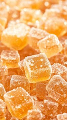 Close-up of shiny orange candy cubes coated in sugar.