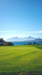 Fototapeta premium Scenic View of an Empty Golf Course with Pristine Green Overlooking a Serene Ocean and Mountain Ranges. Vertical