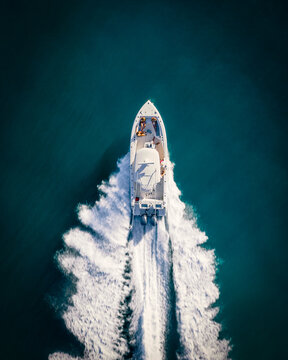 Top down shot of a boat at high speed taken with a drone in deep blue waters of the Caribbean