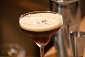 Delicious espresso martini in glass on blurred background, closeup