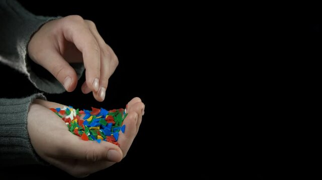 Pollution from microplastic on black. A view of hand with microplastic details against black background.