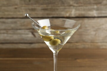 Martini cocktail with olives in glass on table, closeup
