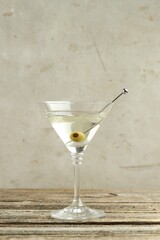 Martini cocktail with olive in glass on wooden table