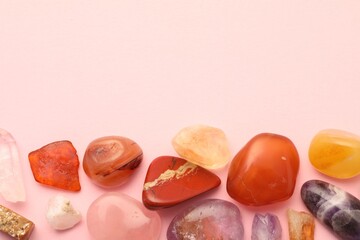 Beautiful natural gemstones on light pink background, flat lay. Space for text