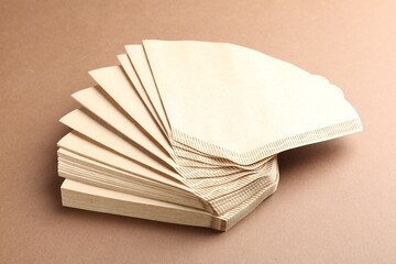 Paper coffee filters on brown background, closeup
